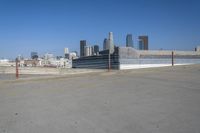 an empty parking lot in a city with skyscrapers in the background of this picture