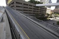 two vehicles drive down a city road next to tall buildings and a parking garage overpass