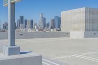 a parking lot with no people on it and skyscrapers in the background with blue sky