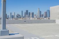 a parking lot with no people on it and skyscrapers in the background with blue sky