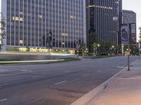 a long city street with two buildings in the background at dusk as seen from a low angle