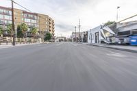 a car and truck going down an empty road with a tall building in the background