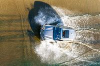 a boat is driving through the shallow water, and its wake is making it's way through