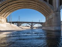 a view of some water under a bridge in a river and the road below has electrical poles on the bridge