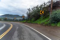 a highway has two yellow traffic signs at the end of the street, and a black gate on the other side