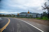 a highway has two yellow traffic signs at the end of the street, and a black gate on the other side