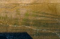 an aerial shot of a person riding a surfboard on the ocean shore line along with a beach in the background