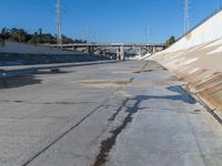 a dirty road and an overpass with power lines going up into the distance above