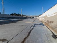 a dirty road and an overpass with power lines going up into the distance above