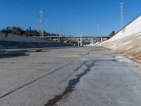 a dirty road and an overpass with power lines going up into the distance above