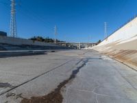 a dirty road and an overpass with power lines going up into the distance above