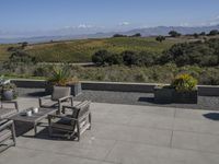 there is a patio table with four chairs outside and a field with mountains in the background