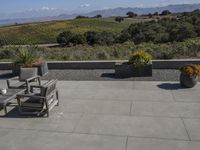 there is a patio table with four chairs outside and a field with mountains in the background