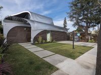 the house is made out of corrugated, white plastic, and is in the grass