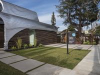 the house is made out of corrugated, white plastic, and is in the grass