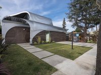 the house is made out of corrugated, white plastic, and is in the grass