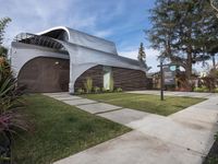 the house is made out of corrugated, white plastic, and is in the grass