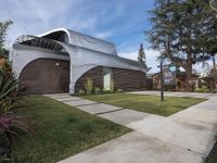 the house is made out of corrugated, white plastic, and is in the grass