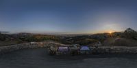 a circular panorama view from a high angle at the overlook at sunrise time shows a person in the foreground, two people and a city on the background