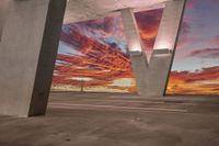 the sky is pink and purple at sunrise near two concrete pillars that appear to be letter v