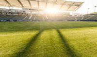 a stadium with some fans in the stands watching a match with the sun peeking through the shade