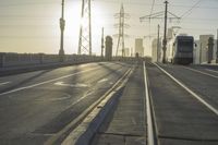 an empty highway with power lines leading to city buildings in the back ground and road tracks