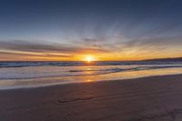 a heart shape drawn in the sand on a beach as the sun sets behind a large mountain