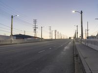 an empty street is shown with lights above it and in the background, power lines