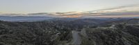 the road winding through the hills is beautiful at sunset in the distance is distant mountains