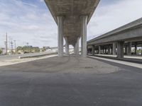 the underpass has concrete columns in it and sky is bright blue and cloudy