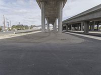 the underpass has concrete columns in it and sky is bright blue and cloudy