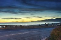 the coast with waves is at the right of this photo, a person riding his motorcycle on the street