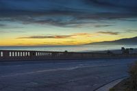 the coast with waves is at the right of this photo, a person riding his motorcycle on the street