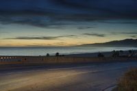 the coast with waves is at the right of this photo, a person riding his motorcycle on the street