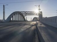 a bridge over a body of water near an intersection at sunset with bright light in the sky