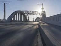 a bridge over a body of water near an intersection at sunset with bright light in the sky