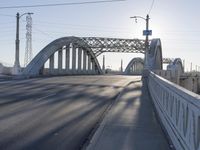 a bridge over a body of water near an intersection at sunset with bright light in the sky