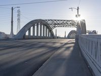 a bridge over a body of water near an intersection at sunset with bright light in the sky