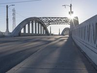 a bridge over a body of water near an intersection at sunset with bright light in the sky