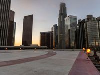 the sun sets over many skyscrapers with red stripes running from the ground to the end