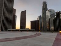 the sun sets over many skyscrapers with red stripes running from the ground to the end