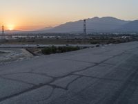 a red stop sign on a street in front of a sunset over a desert mountain