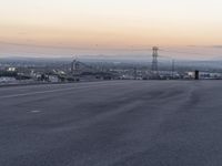 an empty highway with power lines on either side and sunset over the hills in the background