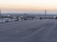 an empty highway with power lines on either side and sunset over the hills in the background