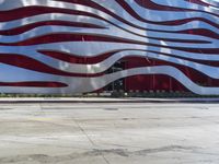 a man is riding a skateboard on the sidewalk by an artistic building that is red and white