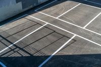 shadow of tennis racket and ball on tarp at court with fenced off parking lot