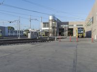 a yellow train pulling into a rail yard next to tall buildings and tracks with overhead power lines