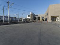 a yellow train pulling into a rail yard next to tall buildings and tracks with overhead power lines