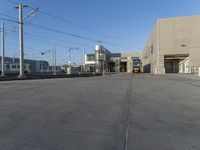 a yellow train pulling into a rail yard next to tall buildings and tracks with overhead power lines