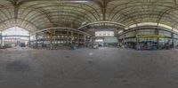 a fisheye lens view of people in an old train station room with a clock and large circular dome